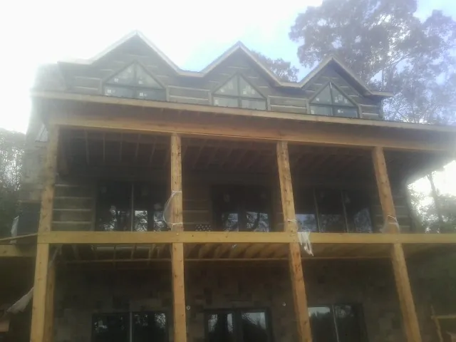 Dormers and porch framing on a large log home under construction — Roof Coating work by our crew in Tokeland