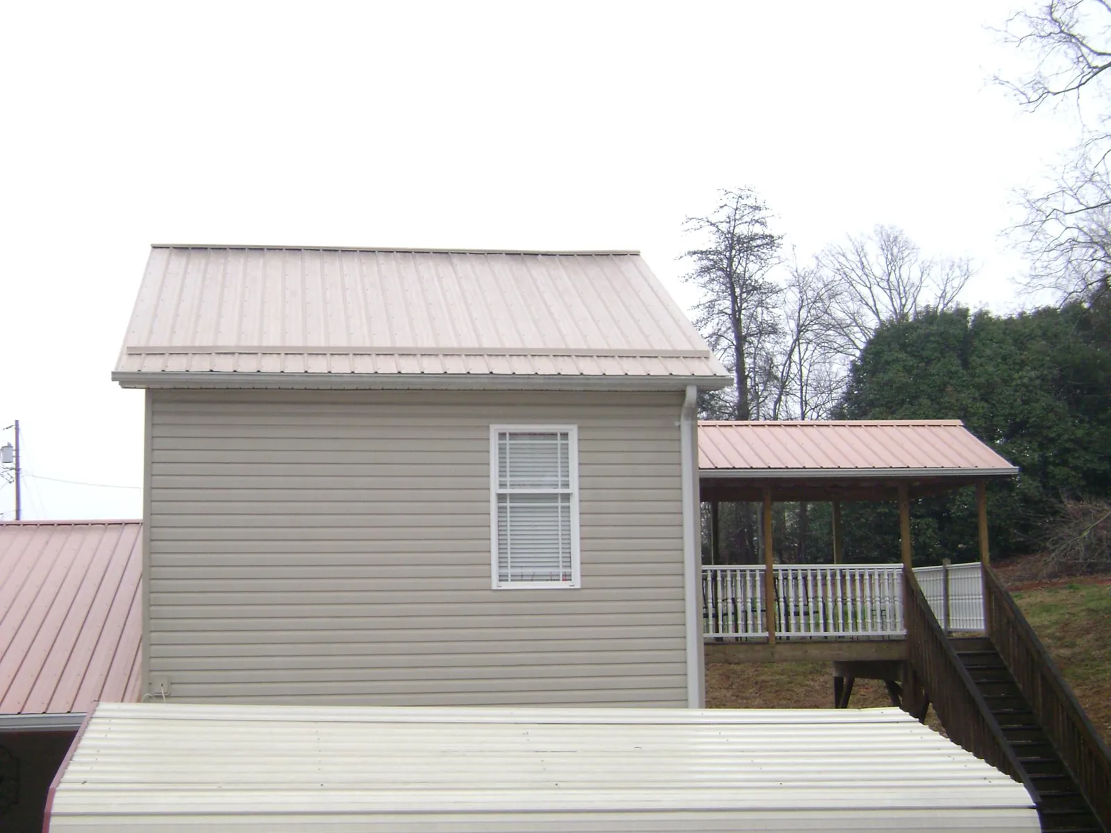 Tan metal roofs on a two story addition and attached porch, from a Roof Replacement job in Tokeland