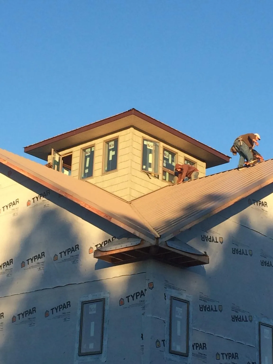 Roofers working around a rooftop cupola on a new metal roof at sunset — Roof Waterproofing in Tokeland by Roofing Brothers